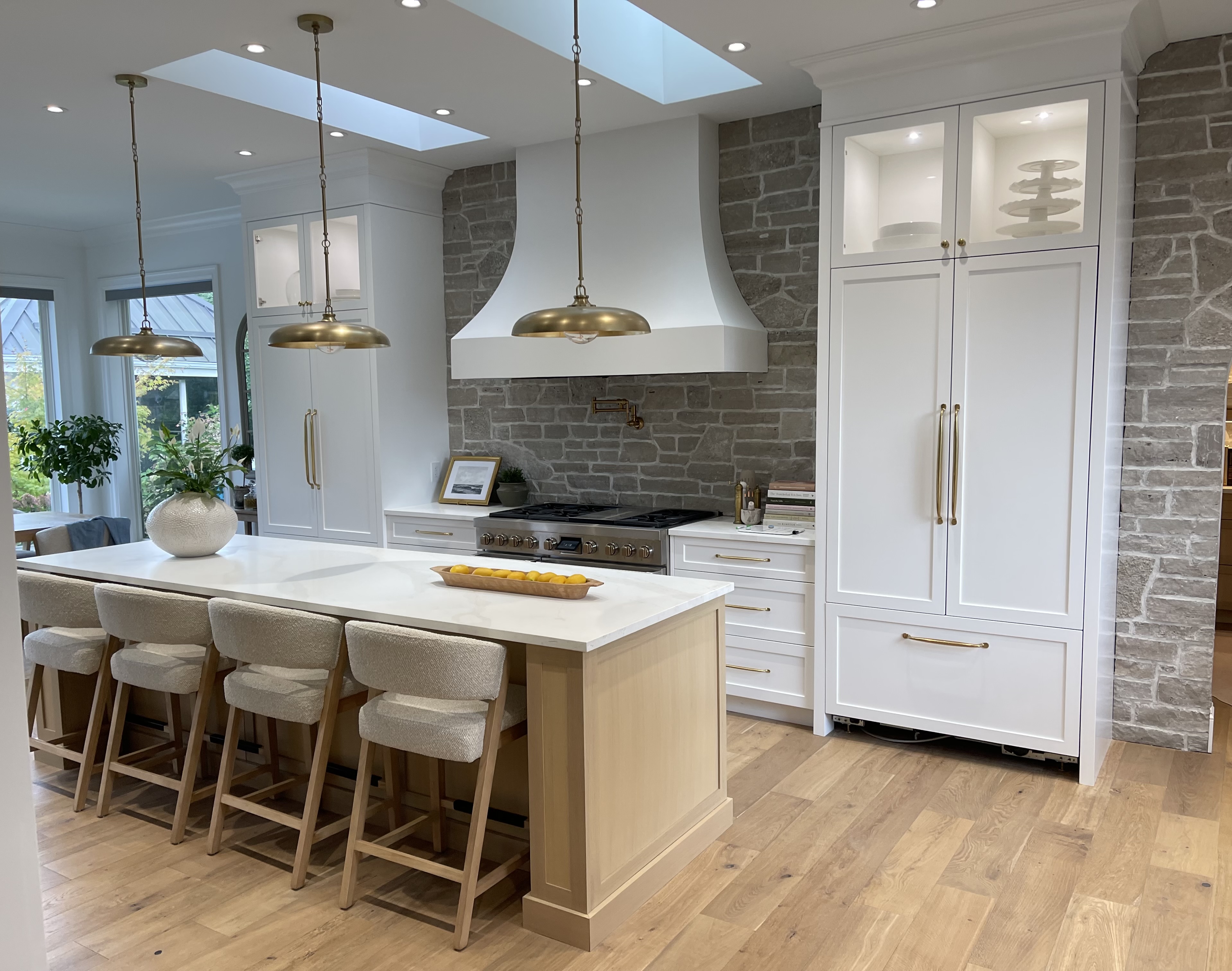 Custom kitchen with stone wall and brass pendants